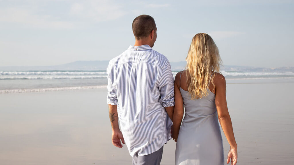 couple waling along beach holding hands